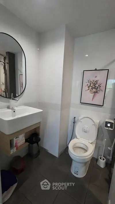 Modern bathroom with sleek design, featuring a round mirror, stylish sink, and elegant wall art.