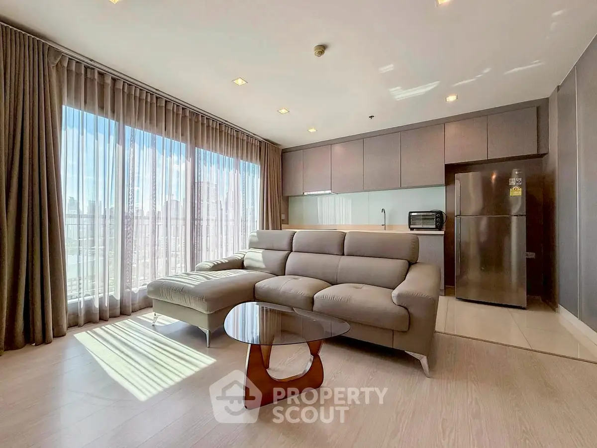 Modern living room with large windows and sleek kitchen in a stylish apartment.