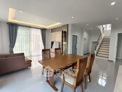 Spacious modern living room with elegant dining area and staircase, featuring sleek design and ample natural light.