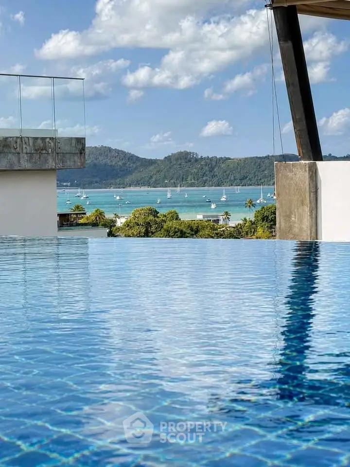 Luxurious infinity pool with stunning ocean view and sailboats in the distance, perfect for relaxation.