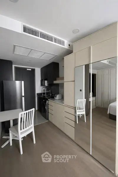 Modern studio apartment with sleek kitchen and mirrored wardrobe