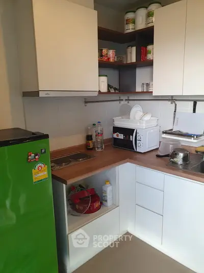 Compact kitchen with green fridge and microwave in modern apartment