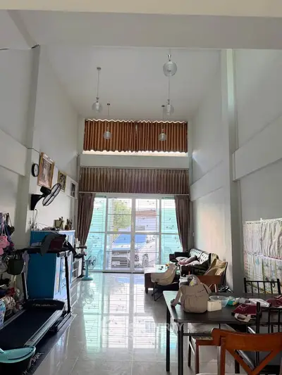 Spacious living room with high ceilings and modern decor, featuring large windows for natural light.