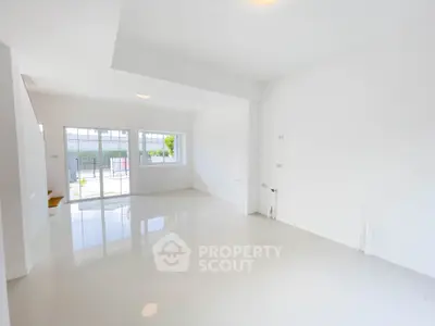 Spacious and bright empty living room with large windows and glossy white tiles.