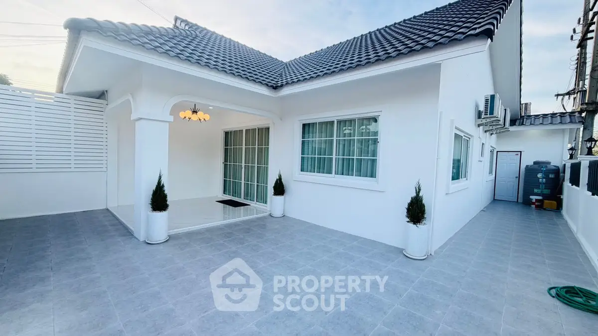 Charming white single-story house with tiled roof and spacious outdoor area.
