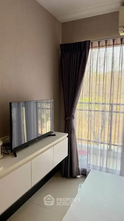 Modern living room with sleek TV setup and natural light from large window.