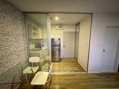 Modern kitchen with glass partition and wooden flooring in a stylish apartment.