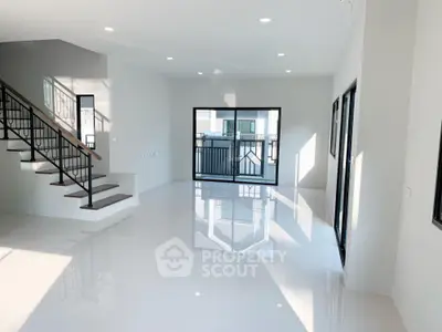 Spacious modern living room with large windows and sleek staircase