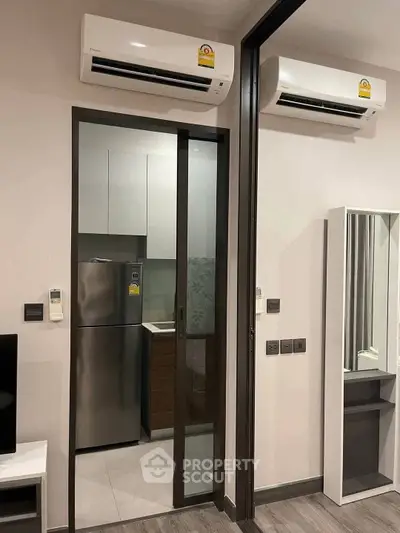 Modern apartment interior with dual air conditioning and compact kitchen view.