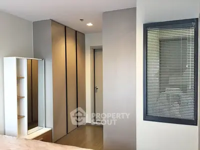 Modern bedroom with sleek wardrobe and large window, perfect for urban living.