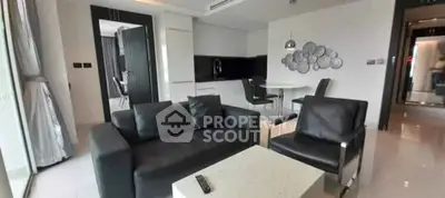 Modern living room with sleek black furniture and open kitchen layout