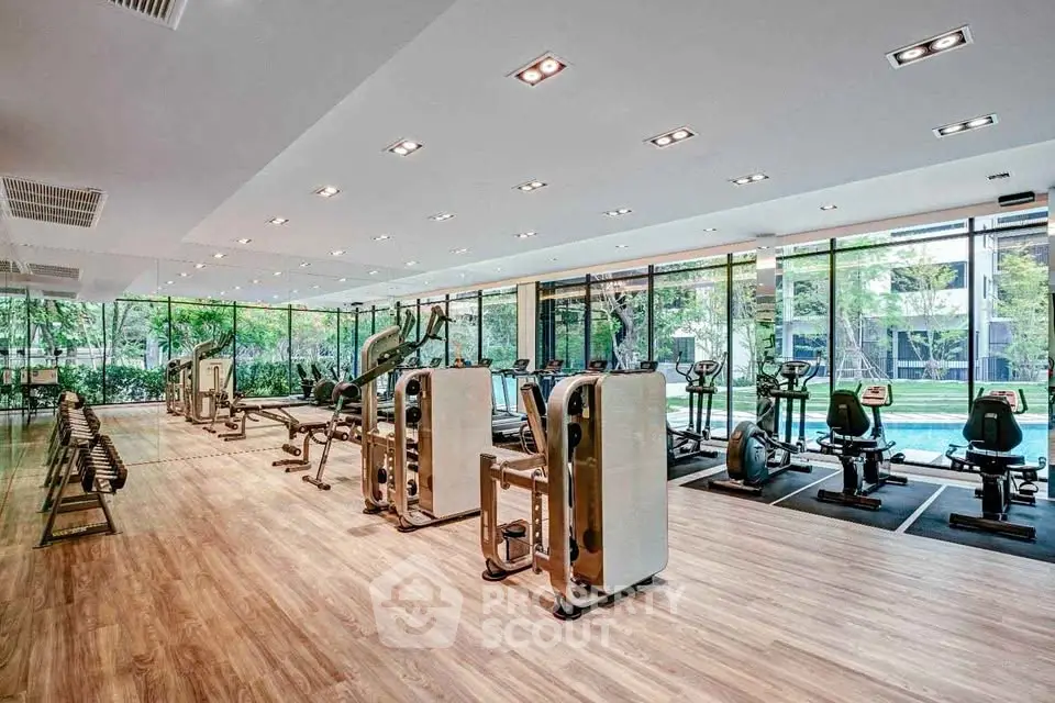 Spacious modern gym with large windows and pool view, featuring state-of-the-art fitness equipment.