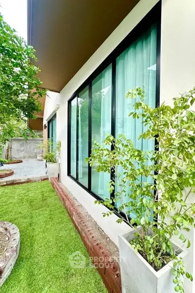 Modern home exterior with large windows and lush garden