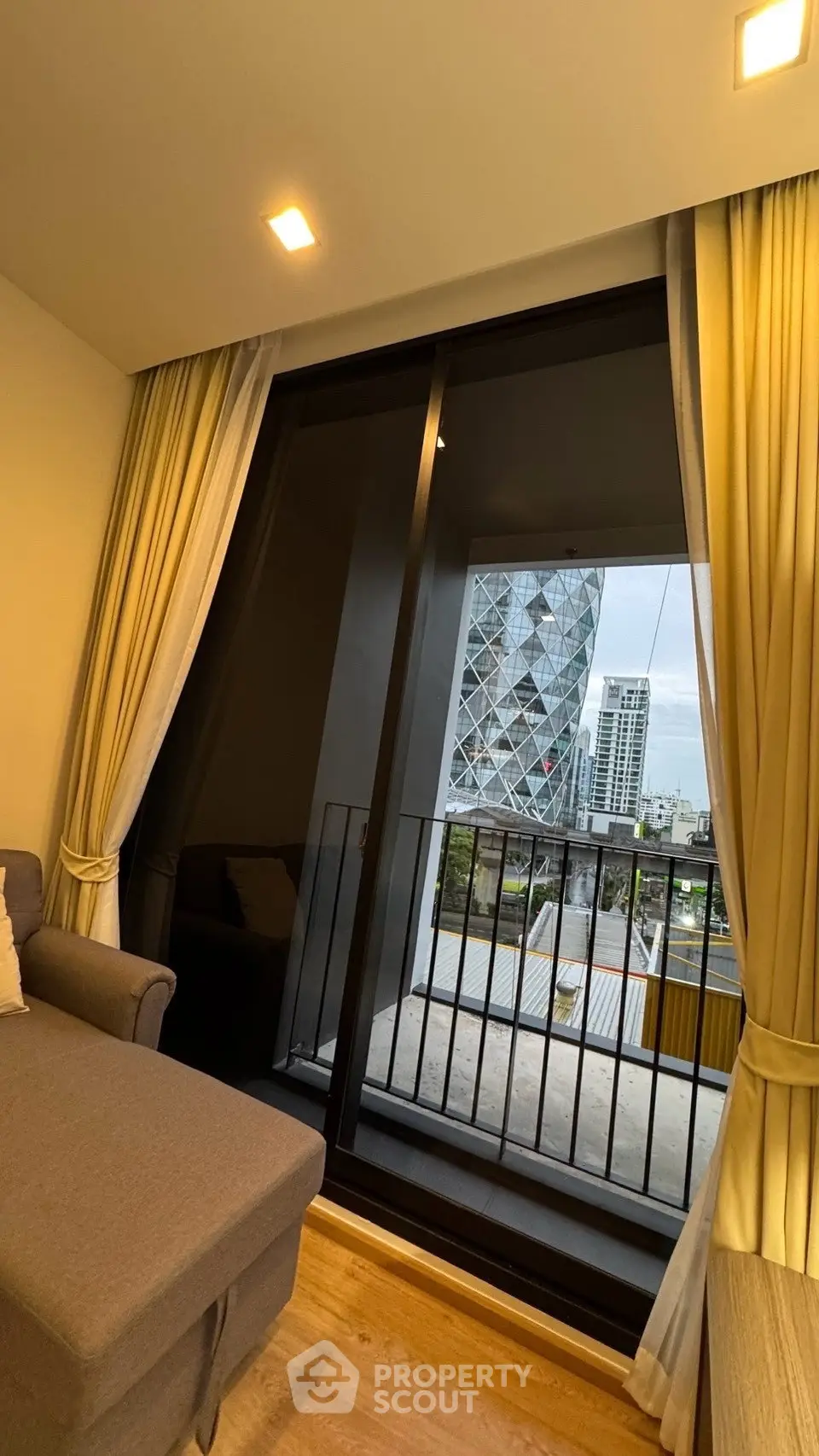 Modern living room with large window offering stunning city view and cozy seating area.