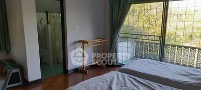 Spacious bedroom with large windows and garden view, featuring a cozy interior and natural light.