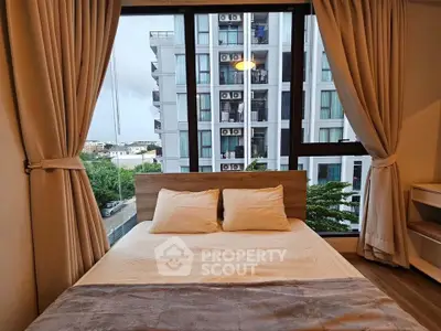 Cozy bedroom with large window offering city view in modern apartment