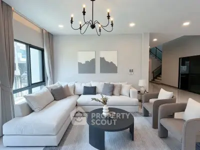 Modern living room with elegant chandelier and cozy seating area.
