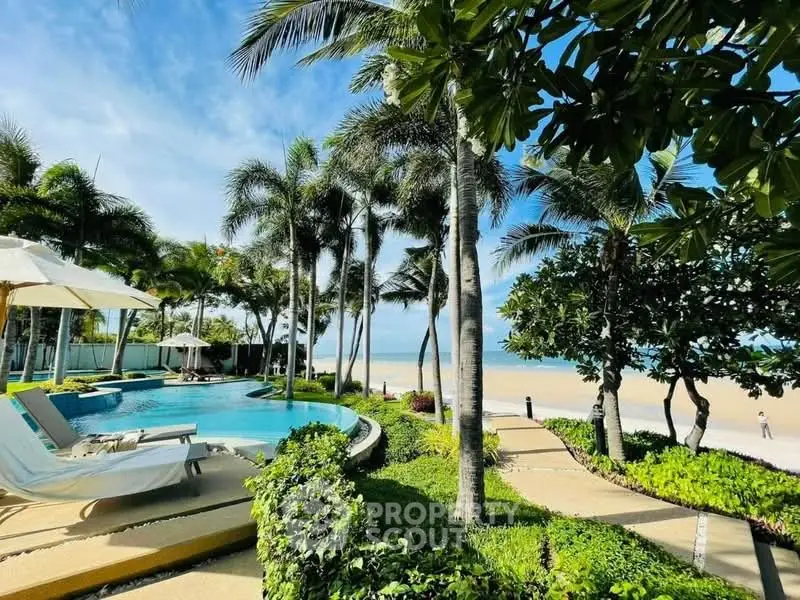 Luxurious beachfront property with pool and lush tropical landscaping, offering stunning ocean views.
