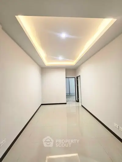 Spacious modern hallway with elegant recessed lighting and glossy tiled flooring.