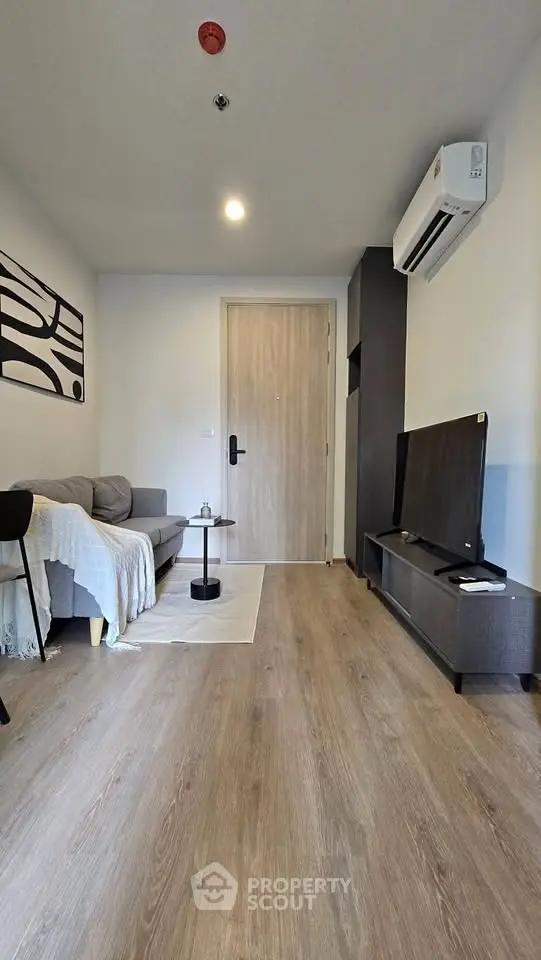 Modern living room with sleek furniture and air conditioning, featuring a cozy sofa and flat-screen TV.