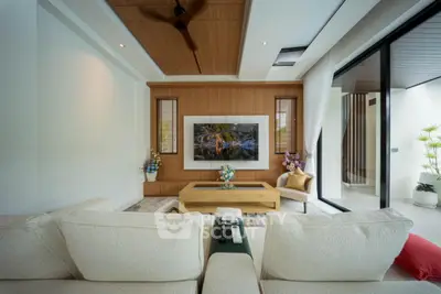 Luxurious modern living room with elegant decor and large TV, featuring cozy seating and natural light.