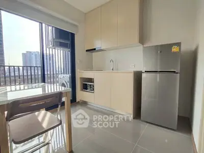 Modern kitchen with sleek cabinets, stainless steel fridge, and city view balcony in a stylish apartment.