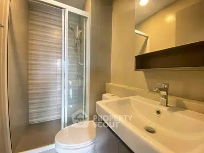 Modern bathroom with glass shower and sleek sink in contemporary apartment.
