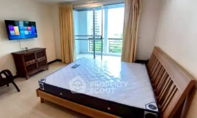 Spacious bedroom with balcony access and modern amenities in urban apartment.