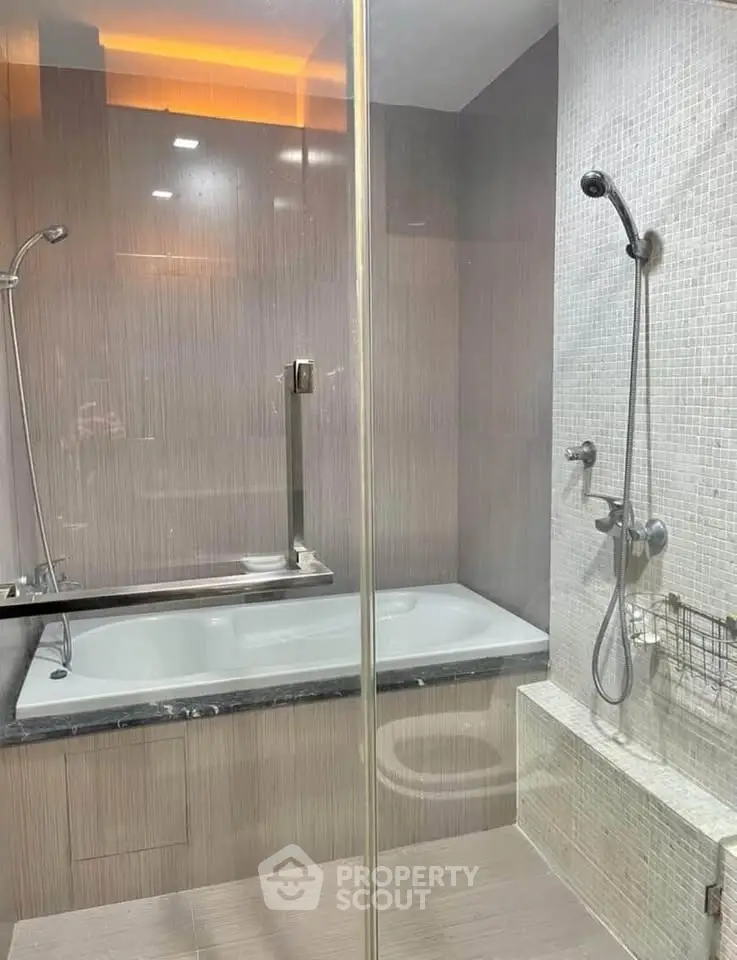 Modern bathroom with glass shower and bathtub in luxury apartment.