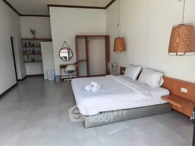 Spacious bedroom with modern decor and natural lighting, featuring a comfortable bed and stylish furnishings.