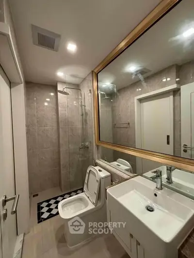 Modern bathroom with glass shower and large mirror in elegant apartment.