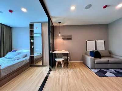 Modern studio apartment with cozy living area and stylish bedroom separated by glass partition.