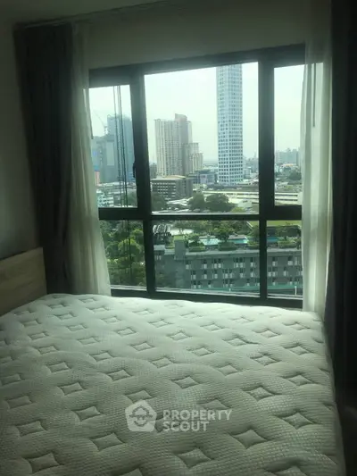 Spacious bedroom with city view from large window, perfect for urban living.
