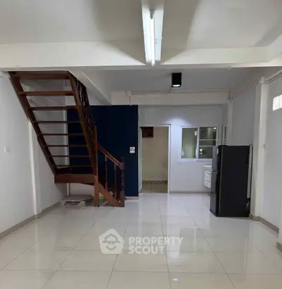 Spacious open-plan living area with modern staircase and sleek tiled flooring.