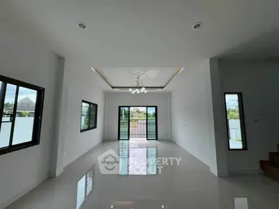 Spacious modern living room with large windows and elegant chandelier, perfect for family gatherings.