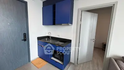 Modern compact kitchen with blue cabinets and sleek design in a cozy apartment.
