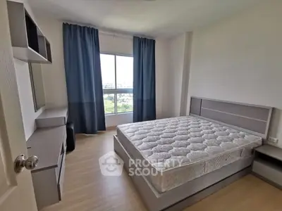 Spacious bedroom with large window and modern furnishings, offering a serene view.