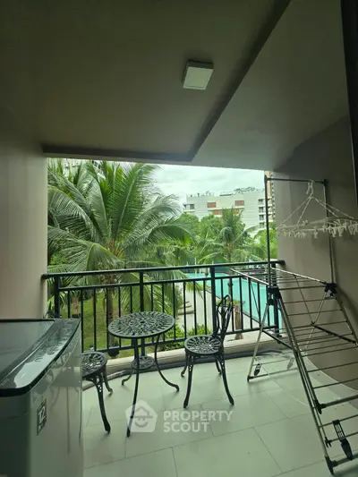 Charming balcony with pool view, featuring elegant outdoor furniture and lush greenery, perfect for relaxation.