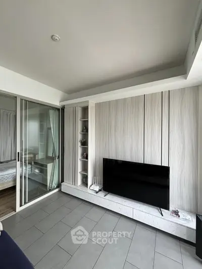 Modern living room with sleek TV setup and sliding glass doors to bedroom