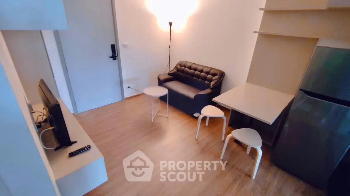 Cozy living room with modern furniture and wooden flooring in a compact apartment.