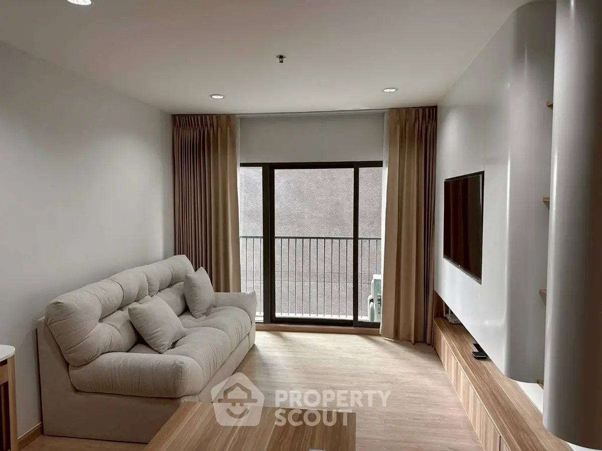 Modern living room with cozy sofa and large TV, featuring a minimalist design and natural light.