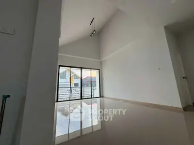 Spacious modern living room with high ceiling and large windows offering abundant natural light.