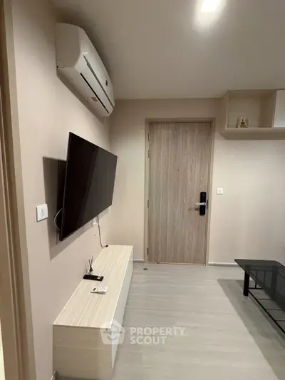 Modern living room with wall-mounted TV and air conditioning in a stylish apartment.