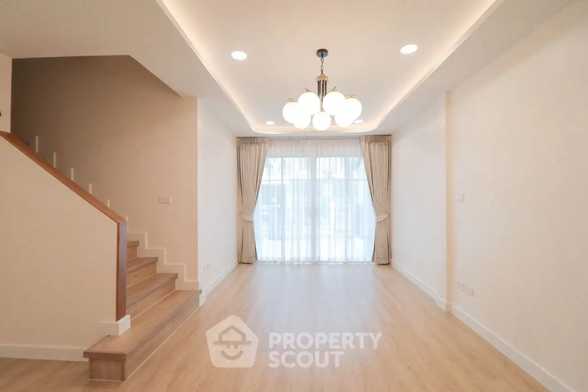 Spacious living room with elegant lighting and wooden staircase