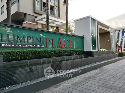 Modern condominium entrance with stylish signage and lush greenery.