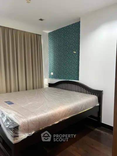 Cozy bedroom with modern decor and large bed, featuring stylish wallpaper accent wall.