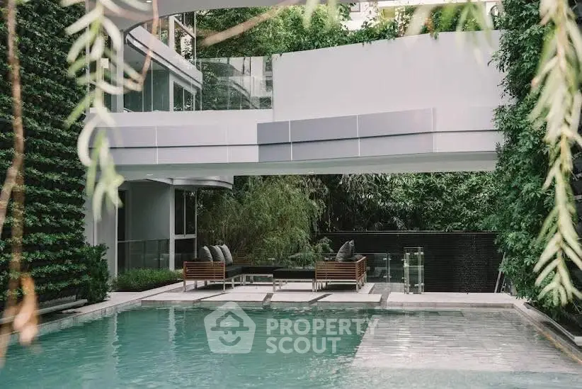 Luxurious modern pool area with lush greenery and stylish seating in a contemporary building.