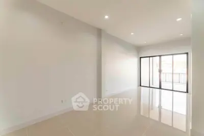 Spacious empty living room with large windows and glossy tiled floors.
