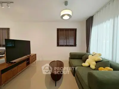 Modern living room with plush green sofa and large TV, perfect for relaxation.