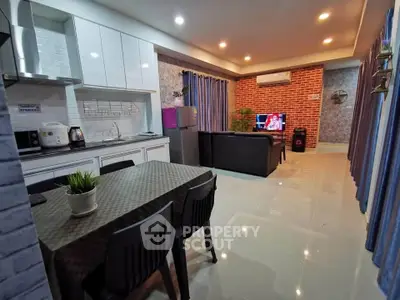 Modern open-layout living room with kitchen, featuring sleek furniture and stylish decor.
